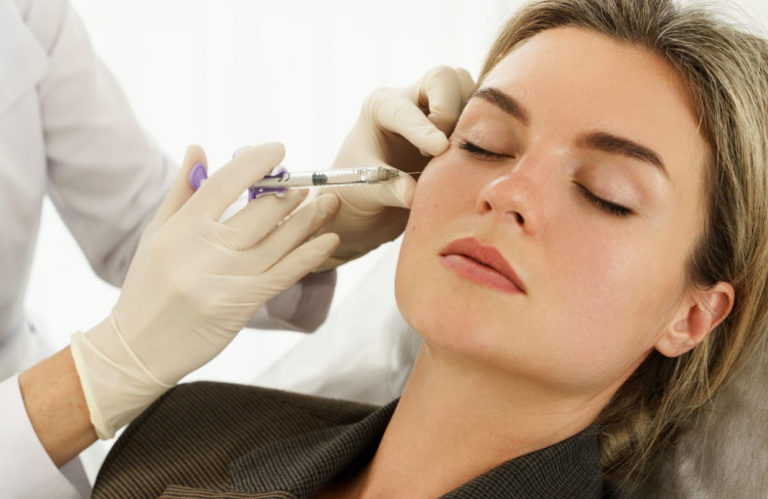 A woman receiving dermal filler injections in her cheek at EstrogenicA clinic