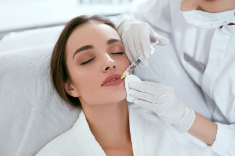 A woman receiving lip fillers in Alabama at EstrogenicA clinic, showcasing a professional aesthetic injector administering the treatment in a sterile and comfortable environment.